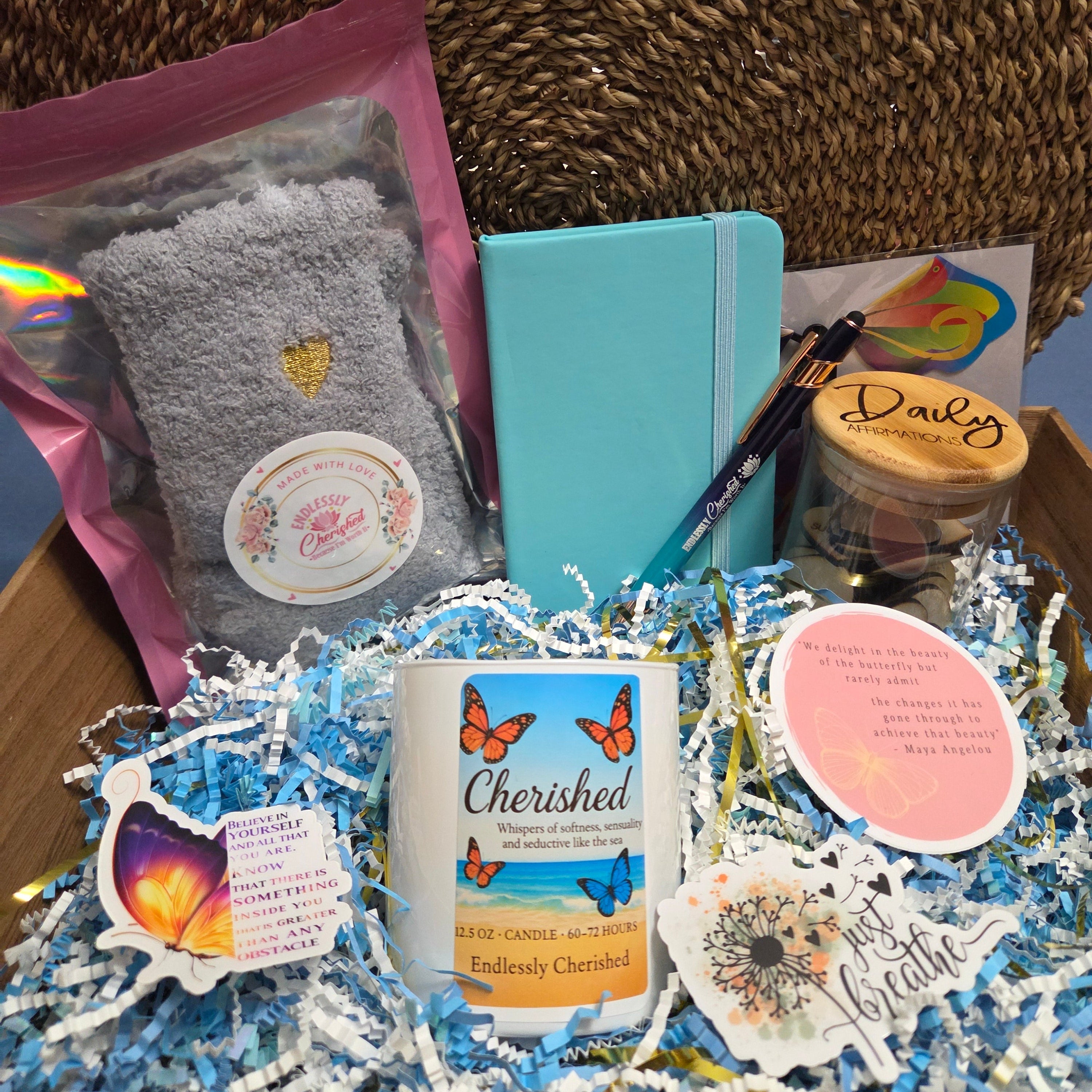 Box with butterfly theme gifts including notebook, socks, pen, candle, stickers, and jar of affirmations