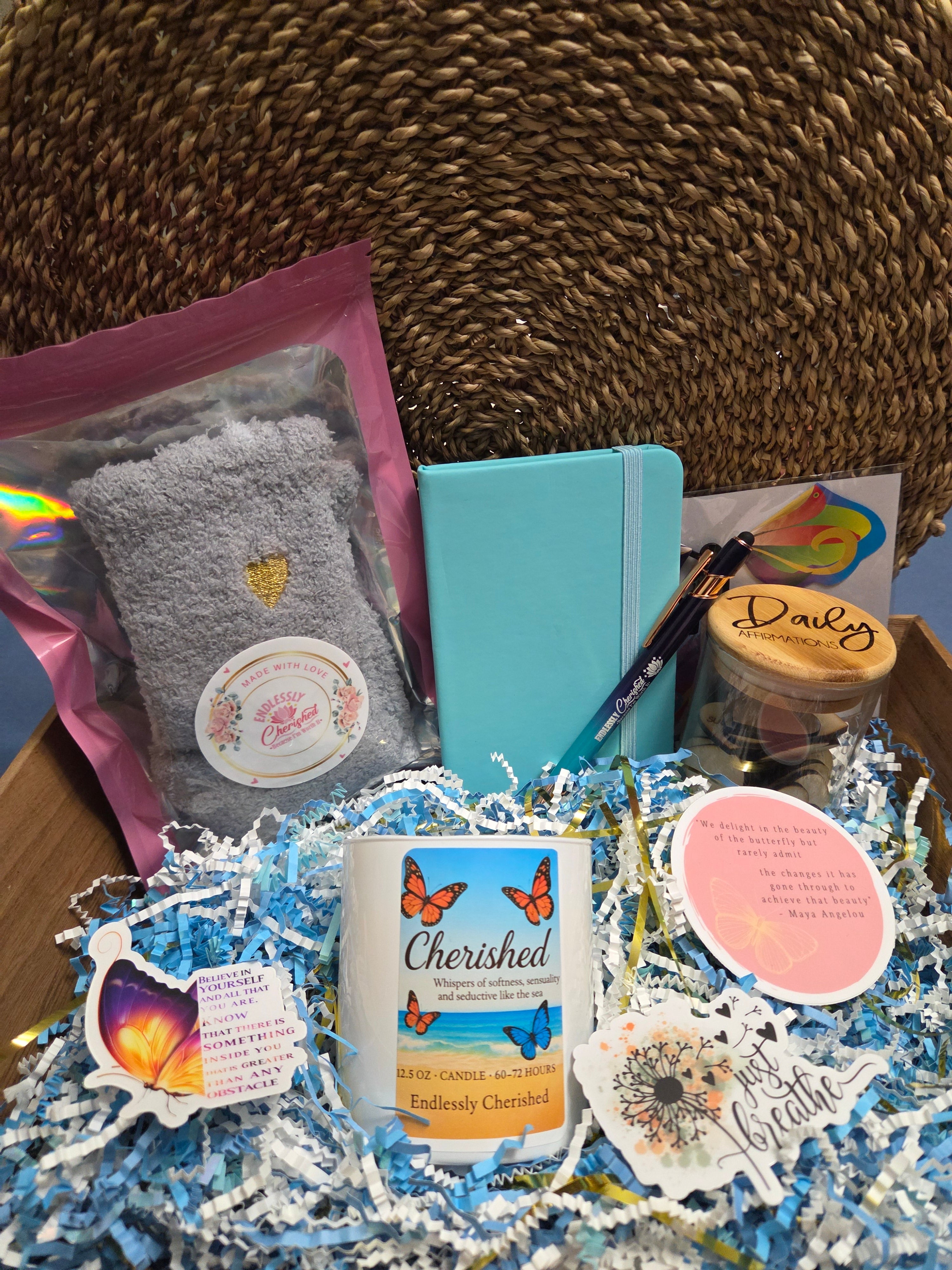 Box with butterfly theme gifts including notebook, socks, pen, candle, stickers, and jar of affirmations